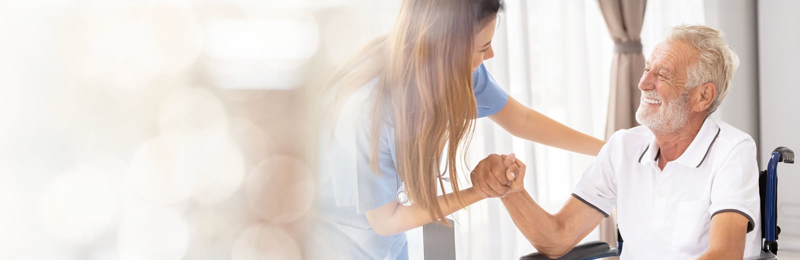 A nurse helping a male patient stand up from a wheel chair
