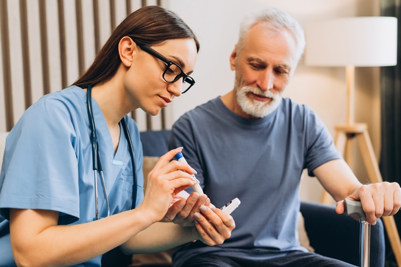 Nurse checking senior man's blood sugar level
