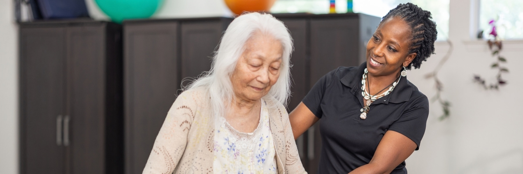 Staff member standing beside a resident during a walking therapy session.